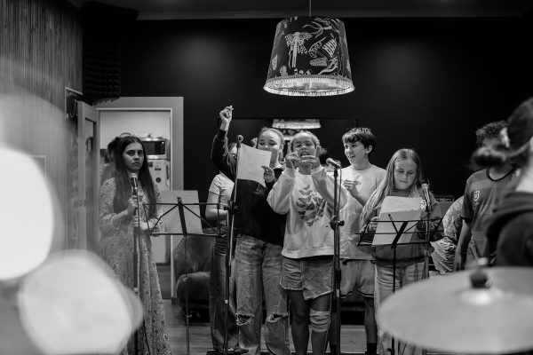 Group of young people singing into a microphone in a b & w ohoto