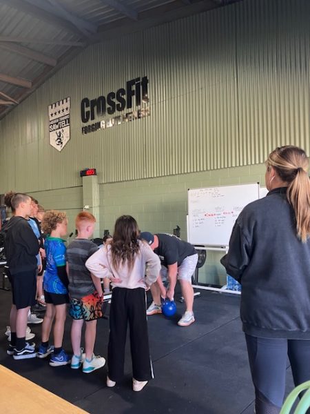 young people standing watching a man lifting a kettle bell at Mission Training gym in Sawtell