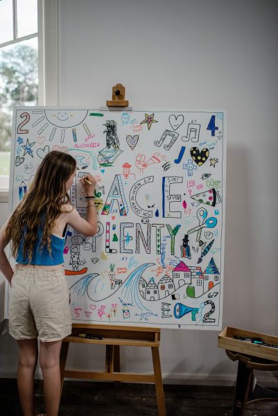 girl with long hair colouring in 'place of plenty' mural
