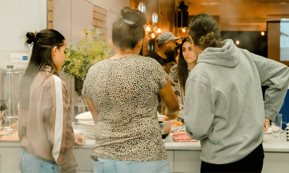 three young women with their back to the camera serving food