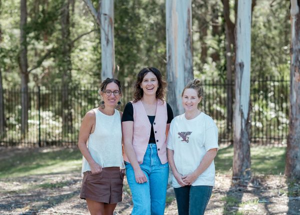 three women standing outside infront of three trees